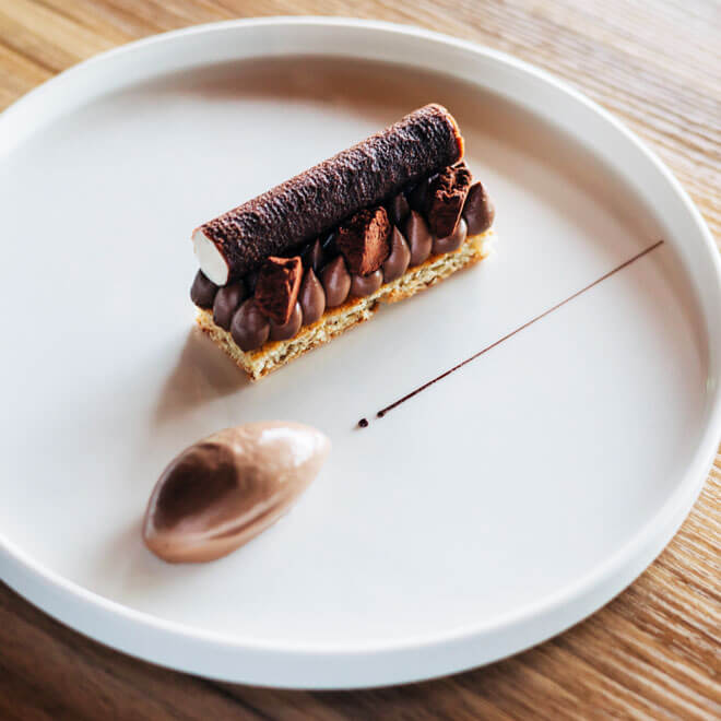 Dessert crémeux au chocolat avec sa mousse légère aux noisettes et son sorbet cacao, le tout délicatement dressé sur une assiette